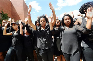 Law students at North Carolina Central University including Chenae Hammond, center, walk in the "hands up, don't shoot" posture during a rally to protest the shooting death of Michael Brown by a white police officer in Ferguson, Mo.,Monday, Aug. 25, 2014, at the Turner Law Building at North Carolina Central University, in Durham. (AP Photo/The Herald-Sun, Bernard Thomas)