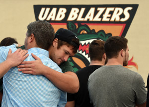 UAB offensive tackle Steve Pickern hugs UAB supporter Justin Craft  after UAB President Ray Watts announced the shut down of the UAB football program Tuesday, Dec. 2, 2014 in Birmingham, Ala. UAB is shutting down the football program after one of the Blazers' stronger seasons.  The university announced the decision Tuesday minutes after President Ray Watts met with the Blazers players and coaches, while several hundred UAB students and fans gathered outside for the third straight day in efforts to support the program. (AP Photo/AL.com, Joe Songer) 