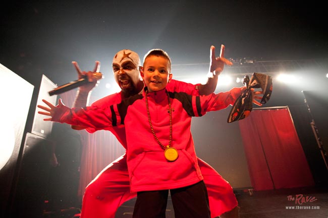 Tech N9ne on stage with an excited fan. Photo via: therave.com