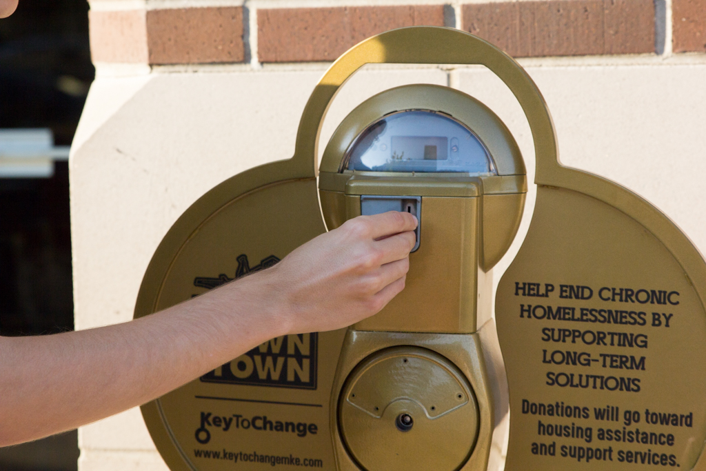 A student dropping a coin in the new Key to Change collection meters. Proceeds go to helping Milwaukees homeless.