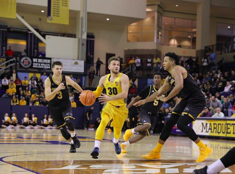 Senior guard Andrew Rowsey drives past two UW-Milwaukee defenders Sunday night. Rowsey finished with a double-double, 12 points and 11 assists in Marquettes 78-63 exhibition win. (Photo by Maggie Bean)