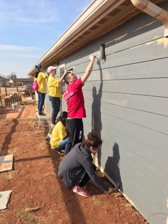 Students work on painting the exterior of a house in Enid, Oklahoma on a Marquette Action Program trip. 
