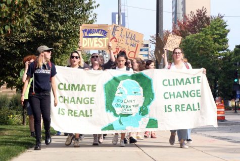 Protestors walk on Wisconsin Avenue with a sign bringing awareness to climate change.