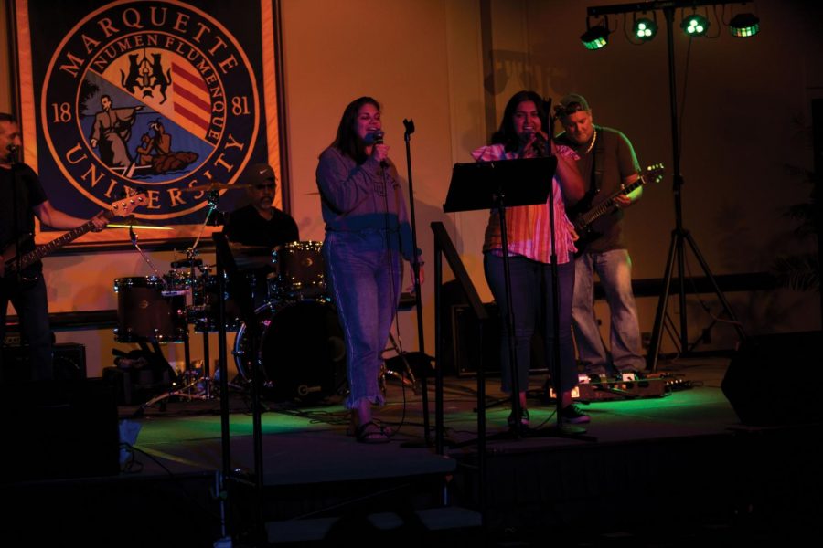 Students sing a duet onstage accompanied by a live band.