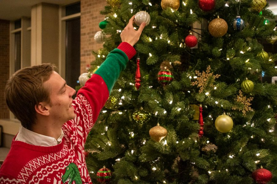 Andrew Fairbank, a junior in the College of Engineering, puts an ornament on a Christmas tree.