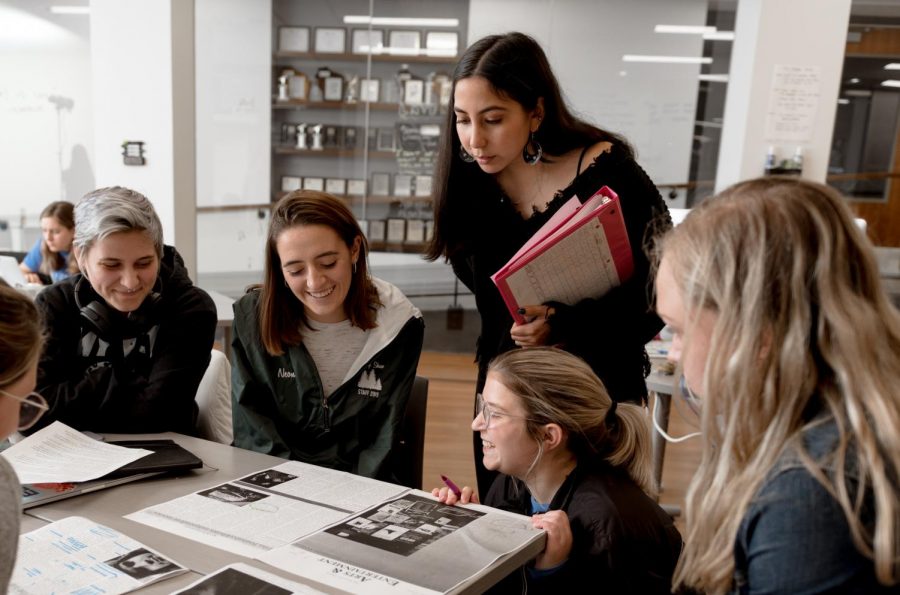 Skyler Daley, Kelli Arseneau, Jenny Whidden, Emma Brauer and Emily Rouse (from left) look over the Arts & Entertainment section of the Marquette Tribune during a production day in fall 2019. Photo courtesy of the Marquette Office of Marketing and Communications.