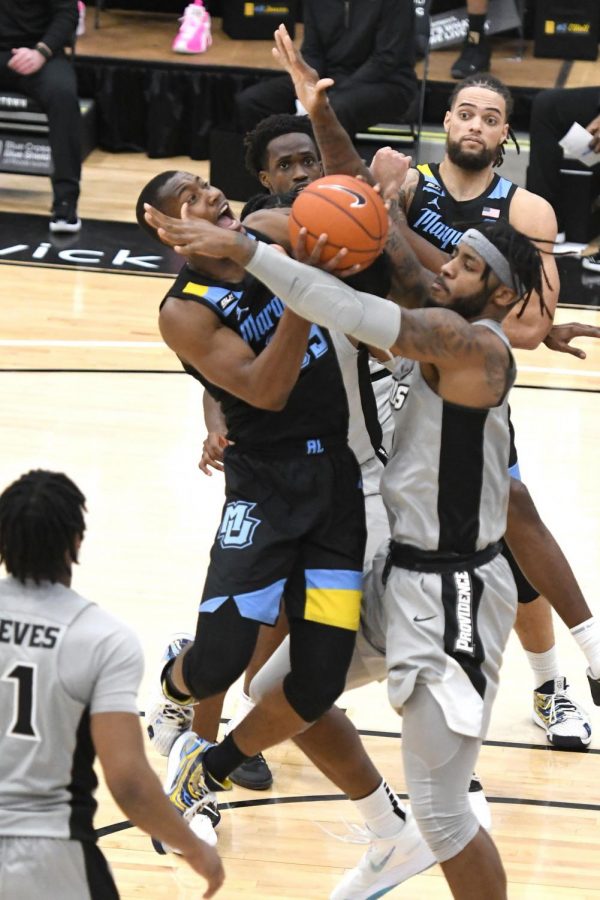 Redshirt senior Koby McEwen (25) attempts to put up a shot through contact (Photo courtesy of Marquette Athletics.)