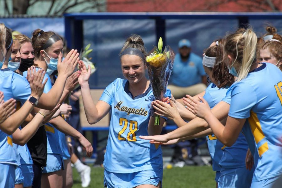 Senior attacker Lindsey Hill receives flowers and high fives teammates during Senior Weekend April 16-18. She scored four goals and tallied one assist Sunday afternoon. (Photo courtesy of Marquette Athletics.)