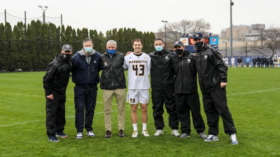 Elliott Yacu (43) poses with Andrew Stimmel (far left), Bill Scholl (second from left) and Michael Lovell (third. from left) at Valley Fields April 10. (Photo courtesy of Marquette Athletics.)