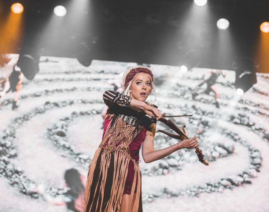 Lindsey Stirling leans back while playing the violin. 
