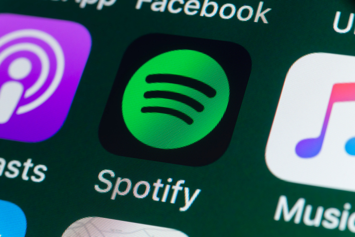 London, UK - July 31, 2018: The buttons of the music streaming app Spotify, surrounded by Podcasts, Apple Music, Facebook and other apps on the screen of an iPhone.