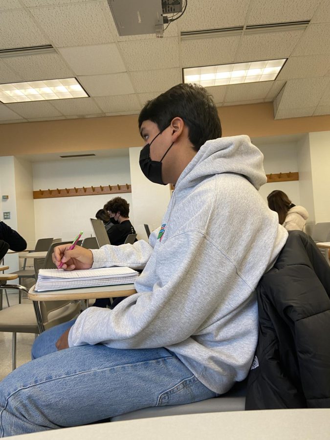 A students wears a face mask while sitting in a classroom. 