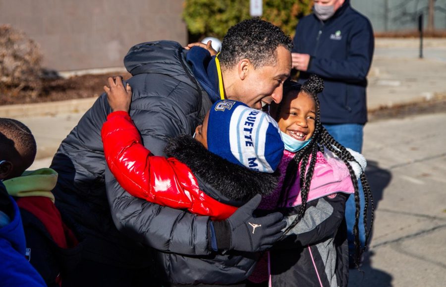 Marquette men's basketball head coach Shaka Smart hugs two students from St. Catherine's Catholic Elementary School at the team's Shopping with the Golden Eagles event at Kohl's Bayshore location Dec. 12. 