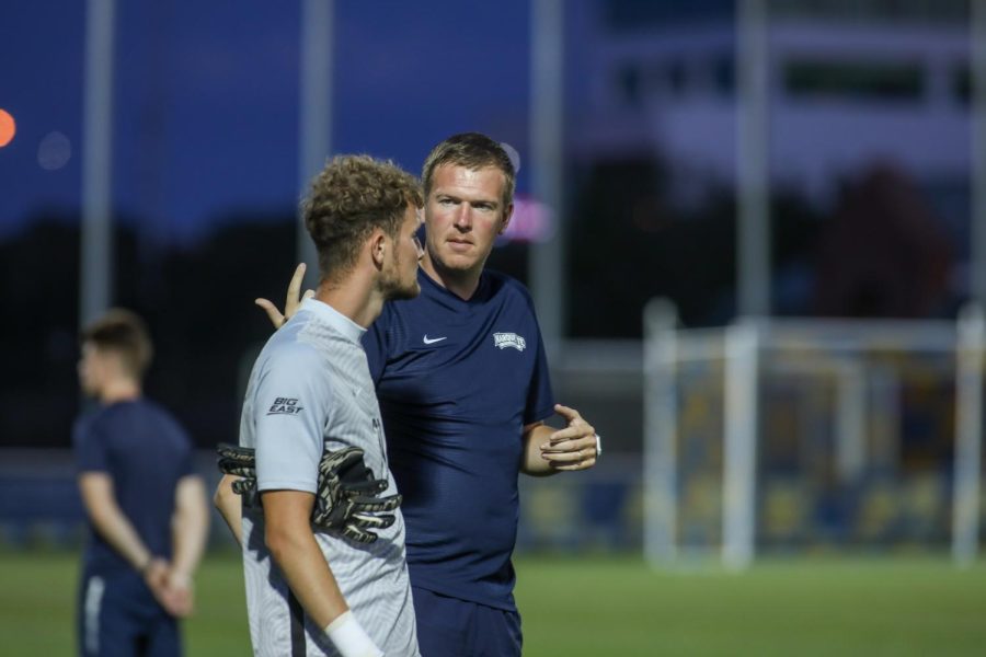 Marquette men's soccer volunteer assistant and goalkeeper coach Graham Shaw (right) talks to senior goalkeeper Chandler Hallwood during the 2021 season. (Photo courtesy of Marquette Athletics.)