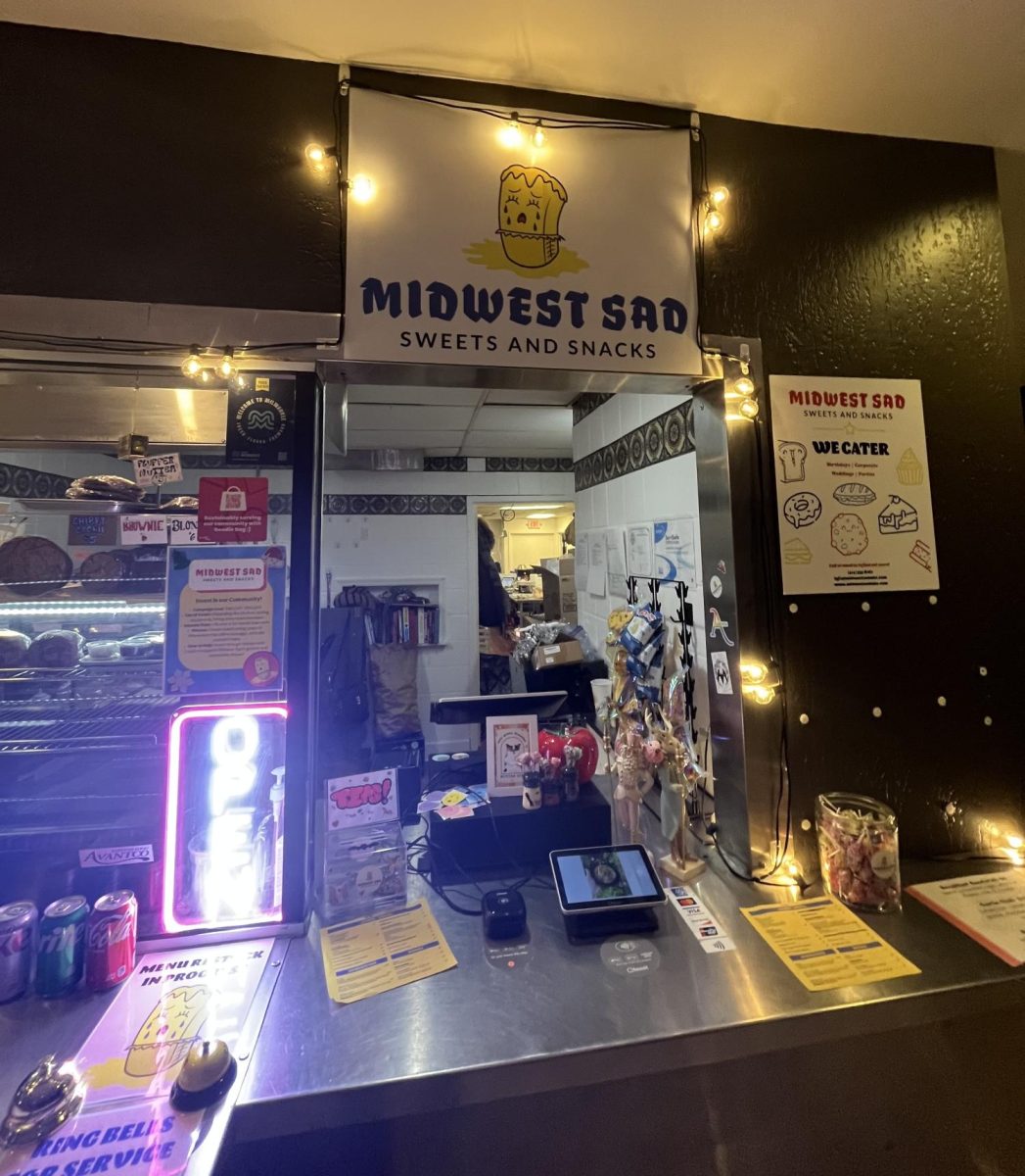 After descending down a set of stairs, the array of cookies, brownies and cinnamon rolls on the shelf complement the subtly lit exterior of Midwest Sad’s ordering window. 